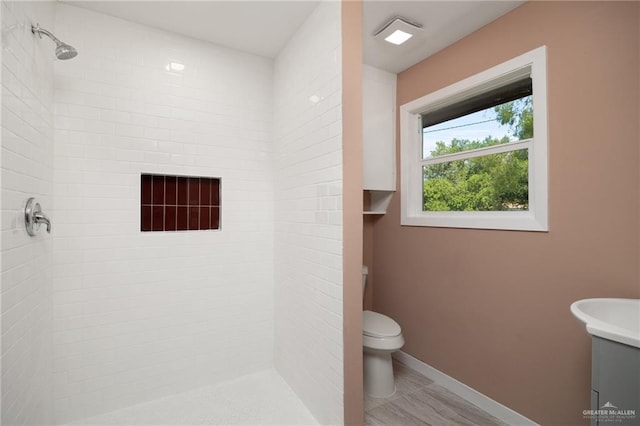 bathroom featuring tiled shower and toilet