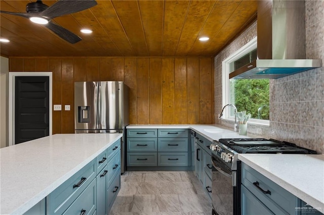 kitchen featuring sink, wood ceiling, ceiling fan, appliances with stainless steel finishes, and wall chimney exhaust hood