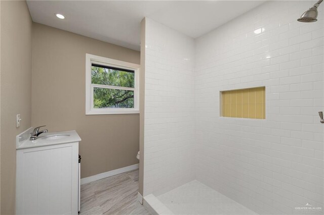 bathroom featuring vanity, a tile shower, and toilet