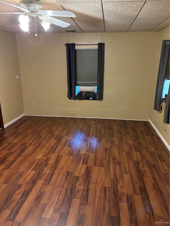 unfurnished room featuring ceiling fan, a drop ceiling, and dark wood-type flooring