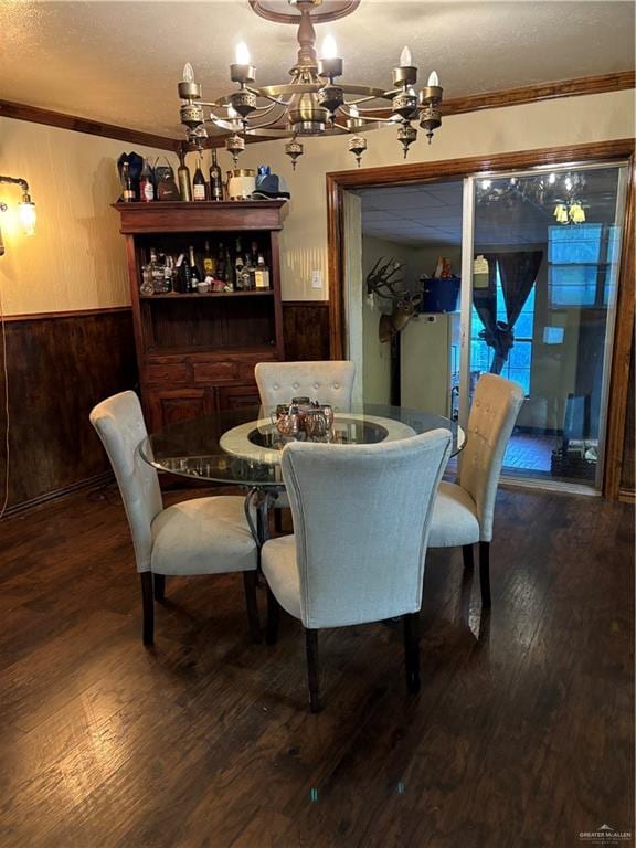 dining area featuring wooden walls, hardwood / wood-style flooring, crown molding, and a notable chandelier