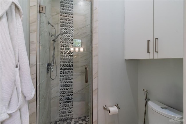 bathroom with a shower with shower door and toilet