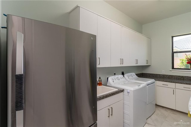 clothes washing area featuring washer and dryer, sink, and cabinets