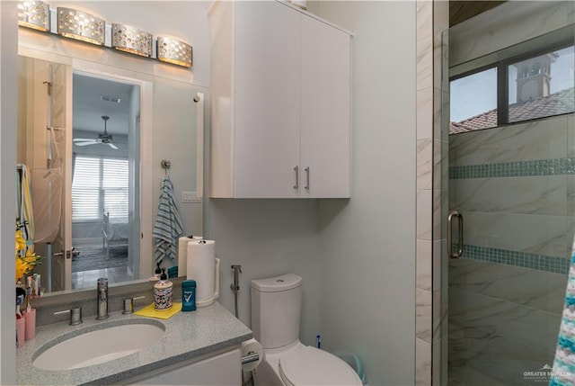 bathroom with ceiling fan, vanity, a shower with shower door, and toilet