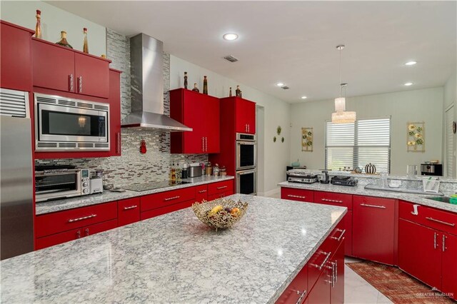 kitchen with built in appliances, tasteful backsplash, light stone counters, and wall chimney range hood