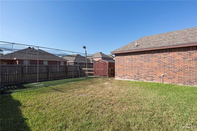view of yard with a storage shed, an outbuilding, and fence private yard