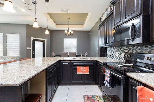 kitchen with tasteful backsplash, a raised ceiling, black electric range oven, stainless steel microwave, and a sink
