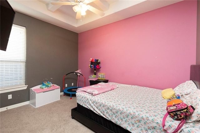 bedroom with ceiling fan, a tray ceiling, carpet flooring, and baseboards