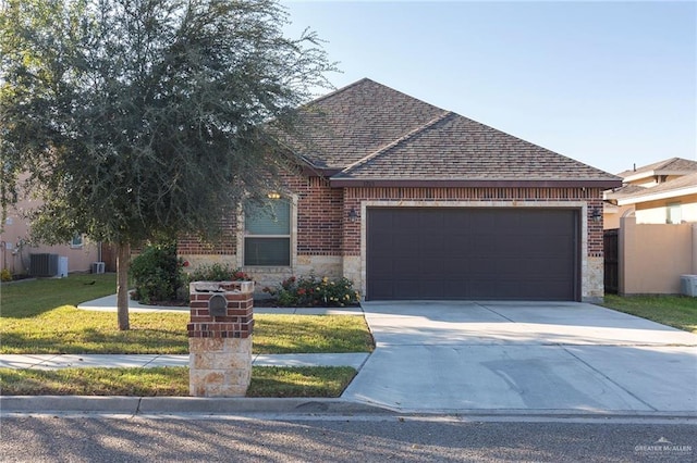 view of front of property featuring a garage, a shingled roof, stone siding, a front lawn, and brick siding