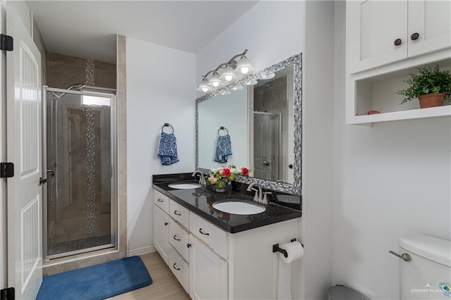 bathroom with a sink, a shower stall, toilet, and double vanity