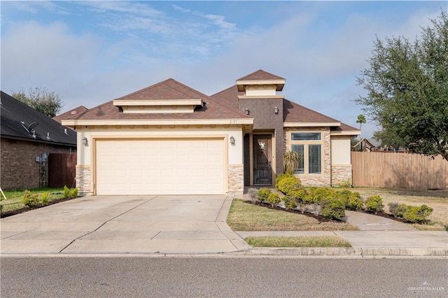 view of front of property featuring stucco siding, fence, a garage, stone siding, and driveway