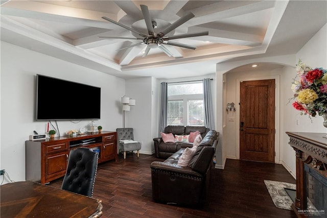 living room featuring arched walkways, dark wood finished floors, a raised ceiling, a ceiling fan, and baseboards