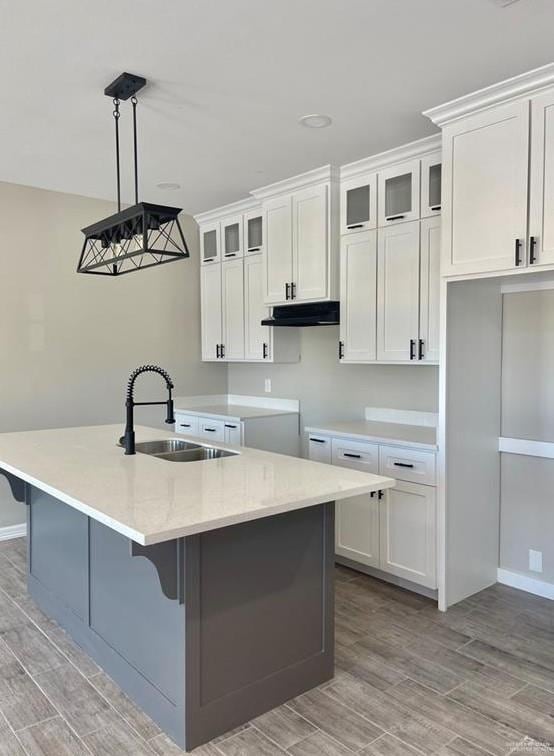 kitchen featuring white cabinets, a center island with sink, and sink