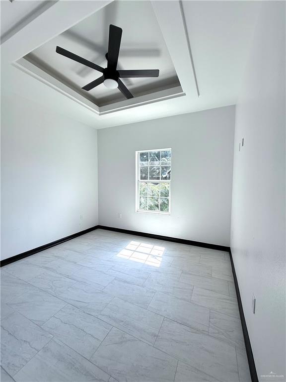 204 S 83rd St, Edinburg, TX 78542 - empty room featuring a raised ceiling, baseboards, a ceiling fan, and marble look tile flooring