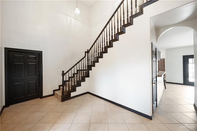 2401 Wisteria Ave, Mcallen, TX 78504 - stairs with tile patterned flooring, arched walkways, a high ceiling, and baseboards