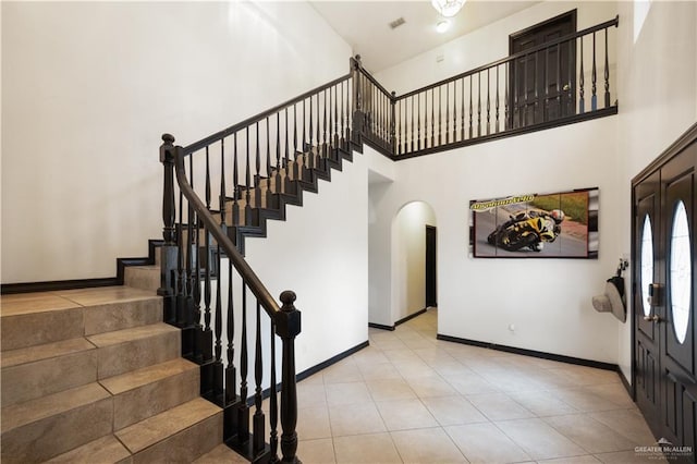 2401 Wisteria Ave, Mcallen, TX 78504 - foyer entrance with arched walkways, stairs, baseboards, a towering ceiling, and light tile patterned floors