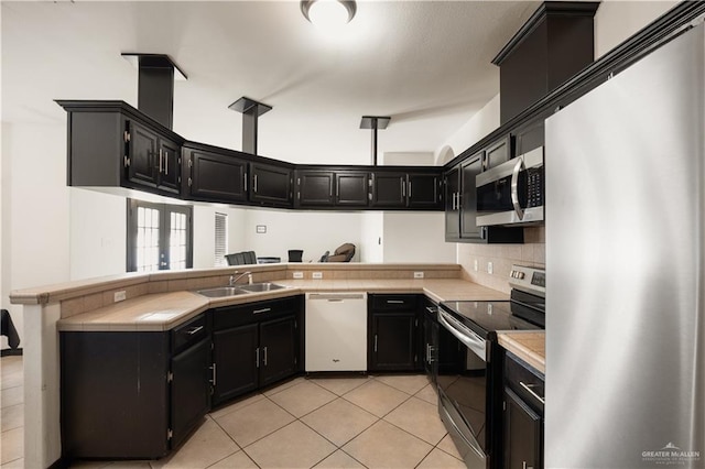 2401 Wisteria Ave, Mcallen, TX 78504 - kitchen featuring appliances with stainless steel finishes, a sink, dark cabinetry, and a peninsula