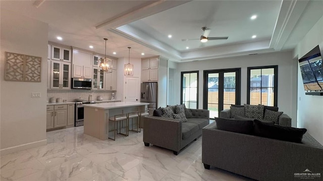 living room featuring french doors, a tray ceiling, and ceiling fan