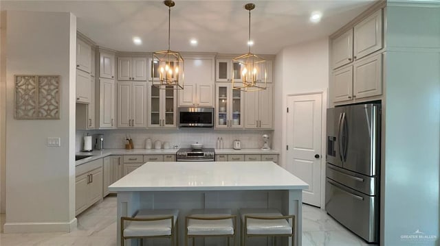 kitchen featuring tasteful backsplash, a kitchen island, stainless steel appliances, and an inviting chandelier