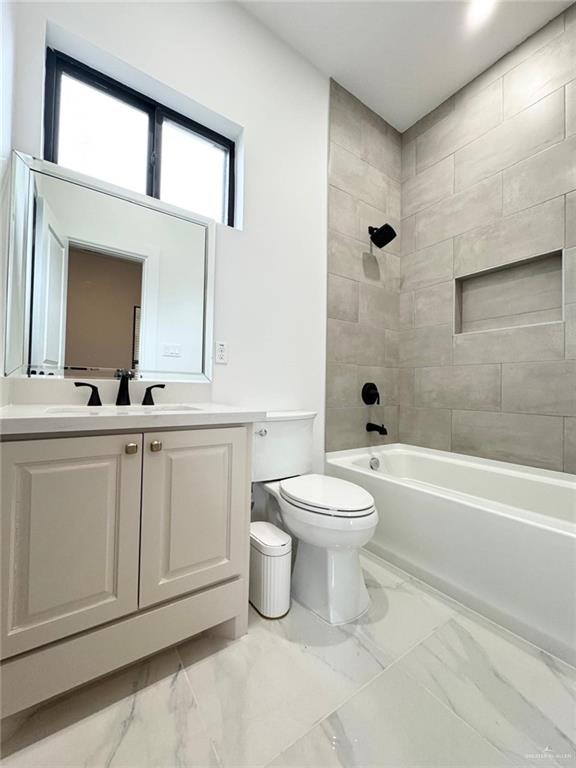 full bathroom featuring tiled shower / bath combo, toilet, and vanity