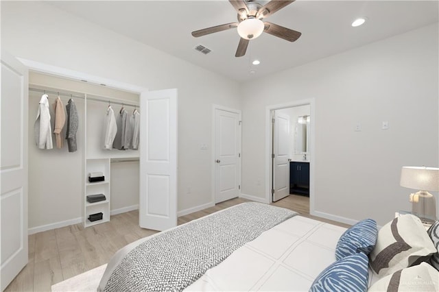 bedroom featuring ensuite bath, light hardwood / wood-style flooring, ceiling fan, and a closet