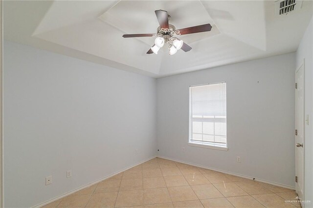 tiled empty room with a raised ceiling and ceiling fan