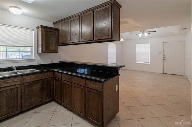 kitchen featuring sink, ceiling fan, dark brown cabinets, light tile patterned flooring, and kitchen peninsula