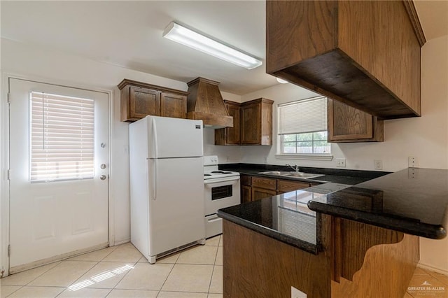 kitchen featuring sink, a breakfast bar area, light tile patterned floors, kitchen peninsula, and white appliances