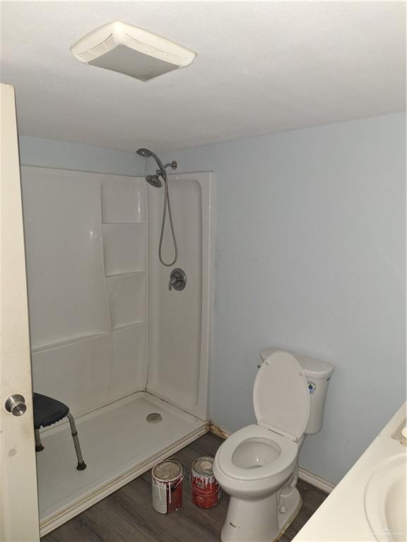 2044 Balboa Ave, Mcallen, TX 78503 - full bathroom featuring wood finished floors, a shower, toilet, and baseboards