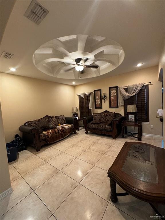 tiled living room with a raised ceiling and ceiling fan