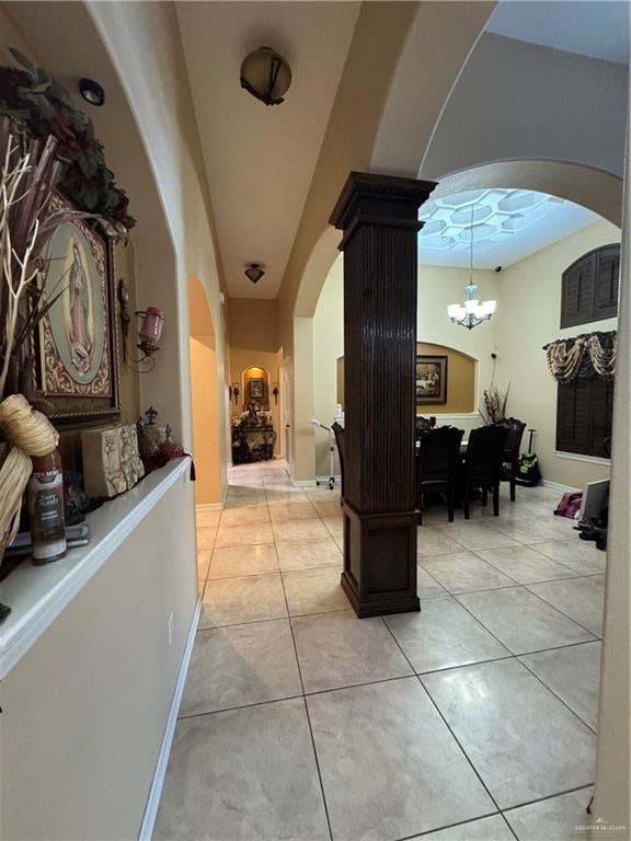 hallway with light tile patterned flooring and a chandelier