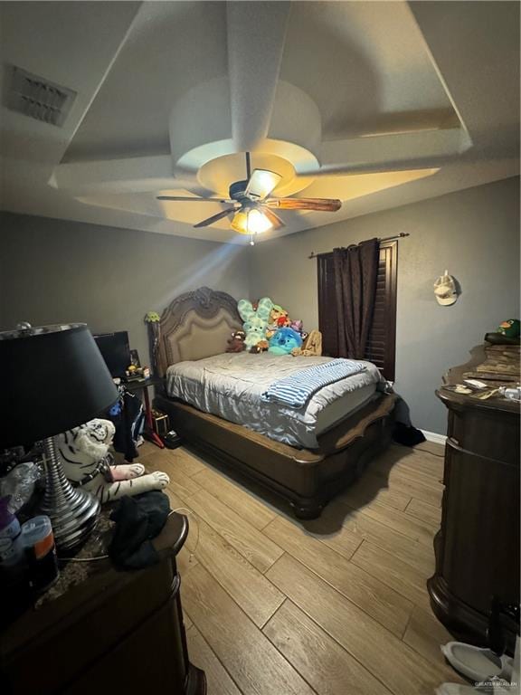 bedroom with a raised ceiling, ceiling fan, and hardwood / wood-style flooring