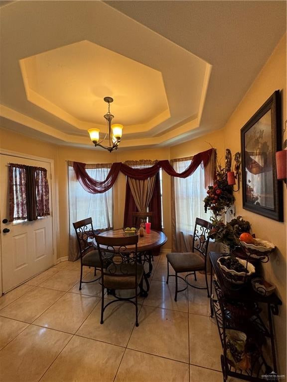 dining space with a raised ceiling, tile patterned flooring, and a chandelier