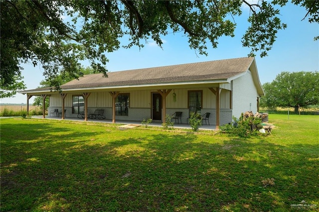 26086 Rabb Rd, La Feria, TX 78559 - view of front of home with a patio area, a front yard, brick siding, a shingled roof, and board and batten siding