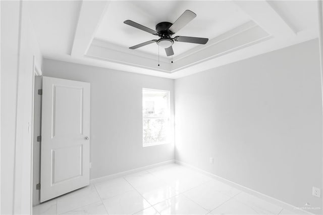 empty room featuring ceiling fan and a raised ceiling