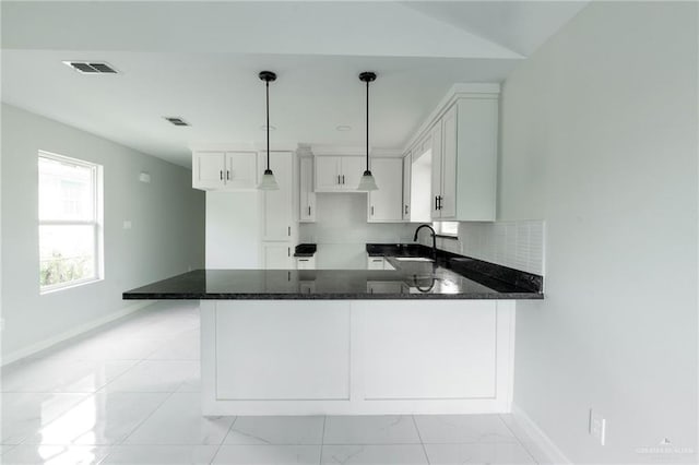 kitchen with white cabinets, sink, hanging light fixtures, dark stone countertops, and kitchen peninsula