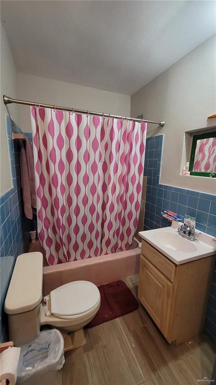 bathroom with toilet, tile walls, a textured ceiling, vanity, and hardwood / wood-style flooring