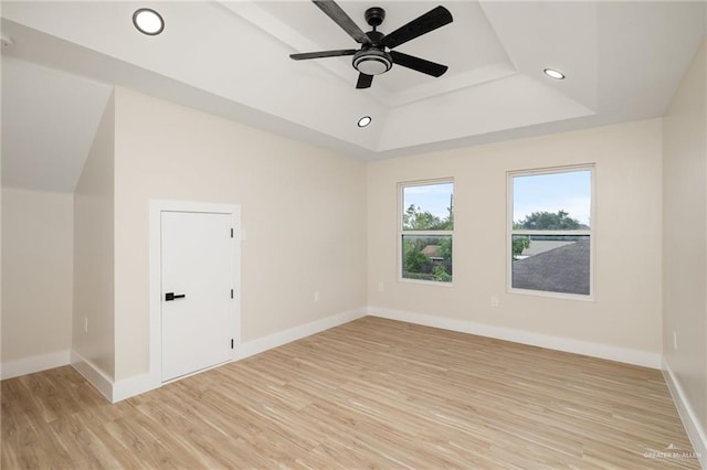 spare room featuring a raised ceiling, ceiling fan, and light hardwood / wood-style floors