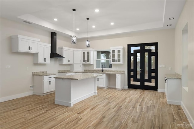 kitchen featuring white cabinetry, wall chimney exhaust hood, and light hardwood / wood-style floors