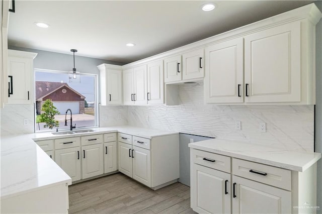 kitchen featuring light stone counters, decorative light fixtures, sink, and white cabinets