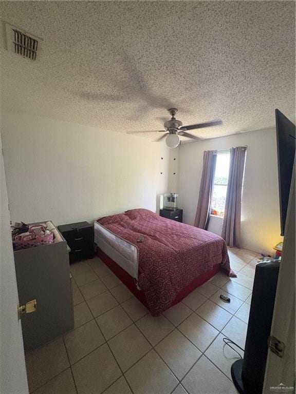 bedroom featuring a ceiling fan, visible vents, a textured ceiling, and light tile patterned floors