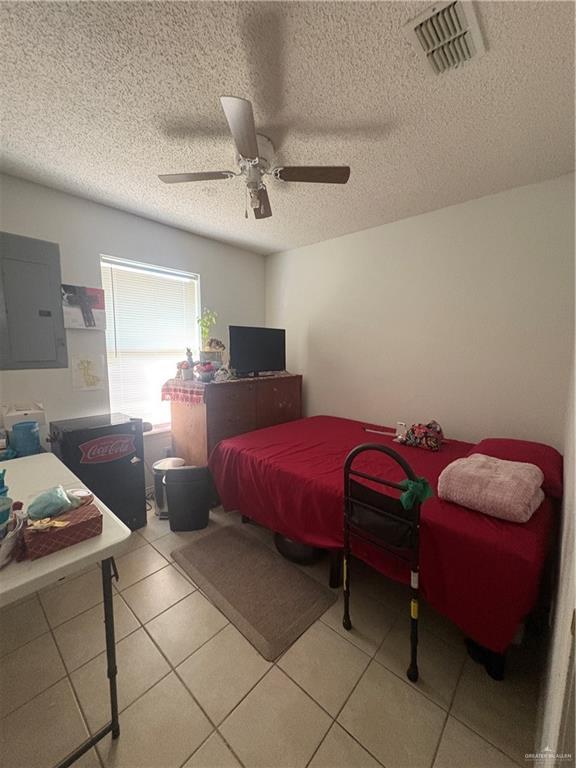 bedroom featuring electric panel, visible vents, ceiling fan, and light tile patterned floors