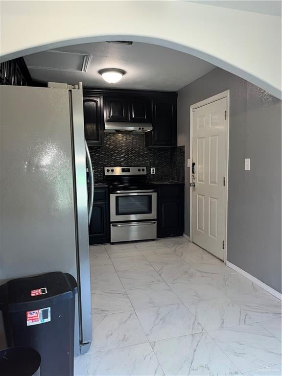 kitchen featuring marble finish floor, under cabinet range hood, stainless steel appliances, and dark cabinets