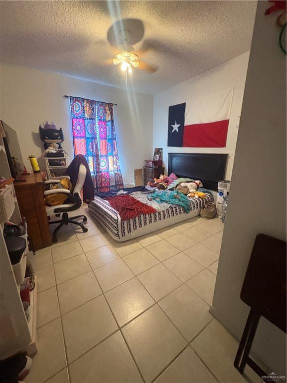 bedroom featuring ceiling fan, a textured ceiling, and tile patterned floors