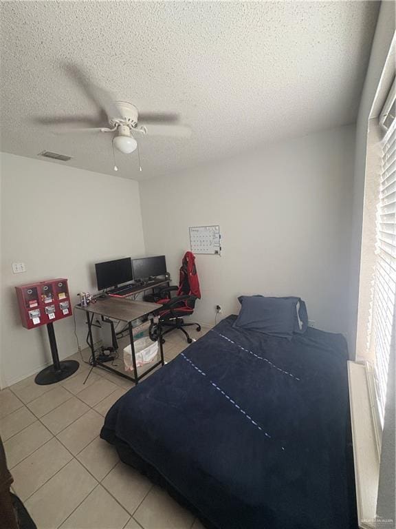 bedroom with a textured ceiling, visible vents, a ceiling fan, and light tile patterned flooring