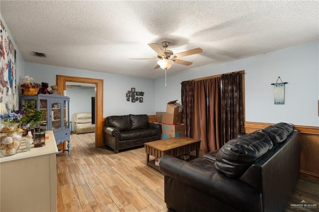 living room with ceiling fan, light hardwood / wood-style floors, and a textured ceiling