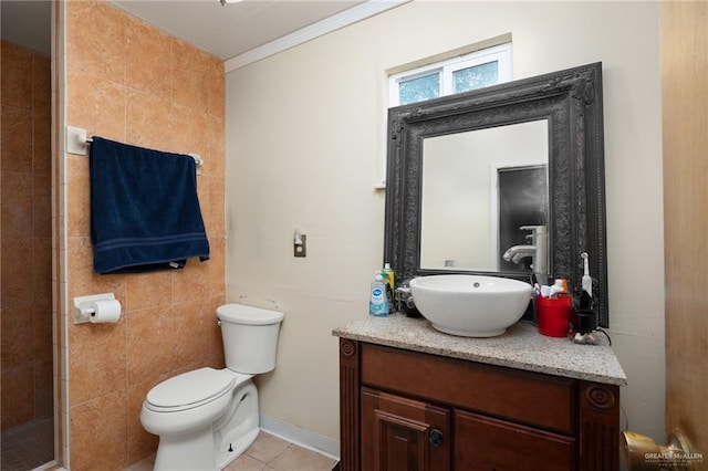 bathroom with tile patterned floors, toilet, crown molding, tile walls, and vanity