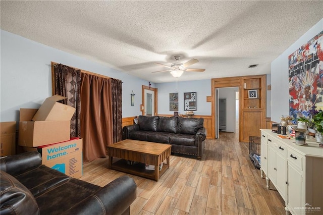 living room with ceiling fan, light hardwood / wood-style flooring, and a textured ceiling