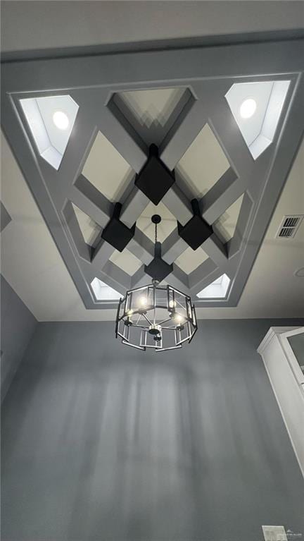 interior details with coffered ceiling, beamed ceiling, and a chandelier