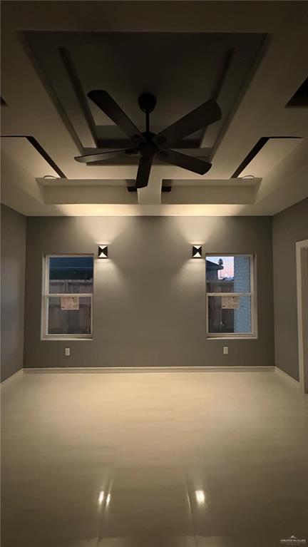 empty room featuring a raised ceiling and ceiling fan